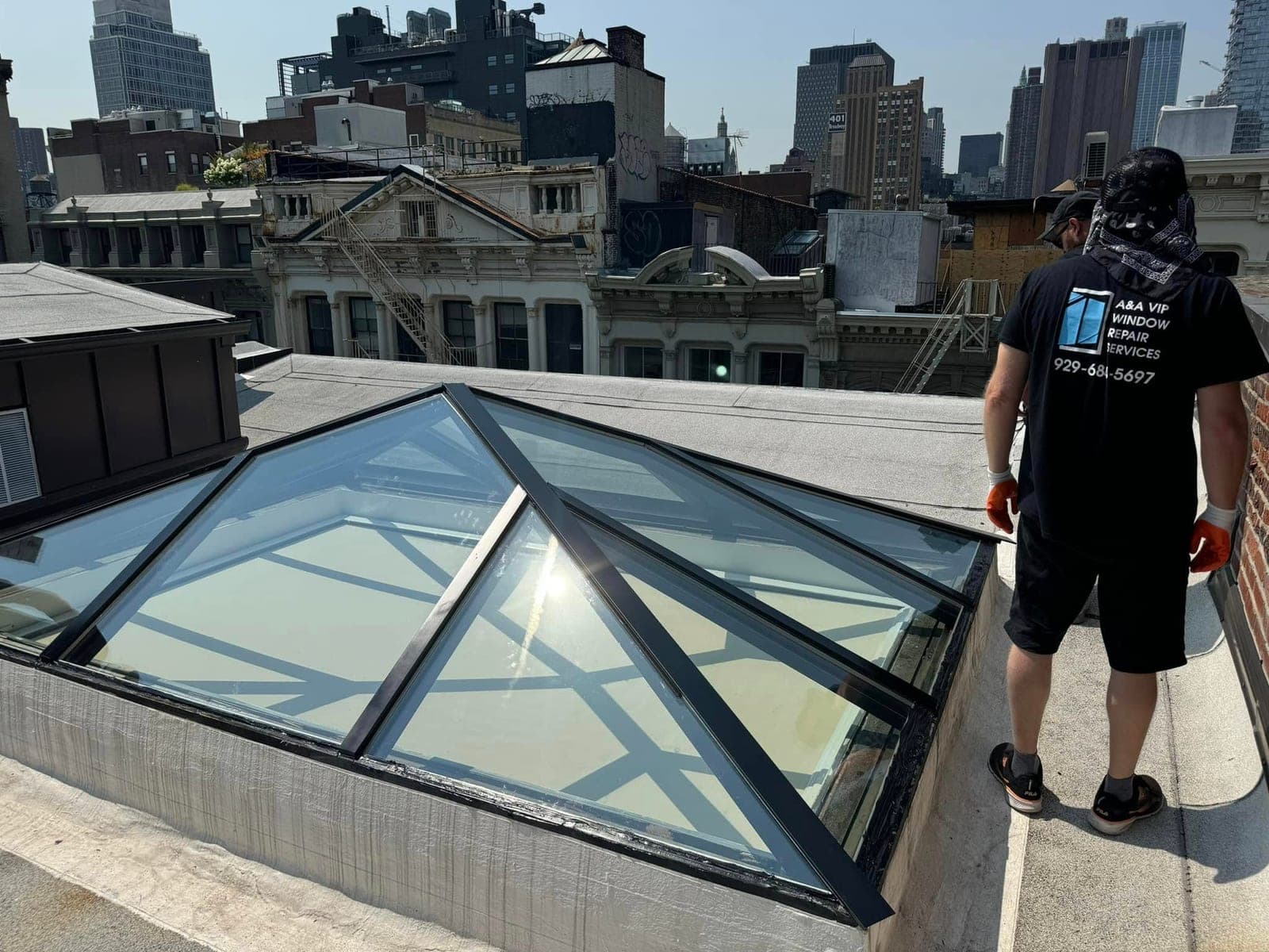 Rooftop glass skylights installed above a building with the New York City skyline behind